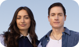 Two people standing side by side with a neutral background