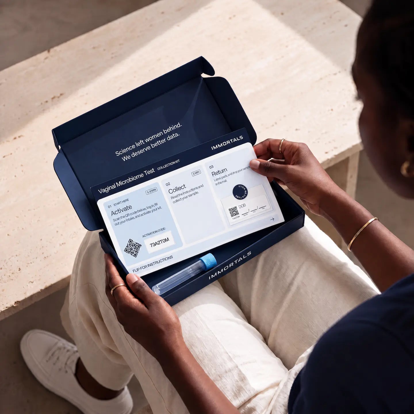 Woman holding an open Immortals vaginal microbiome test kit and reading the instruction card