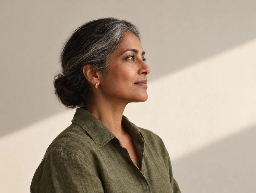 Woman in an olive linen shirt, in profile against a sunlit wall